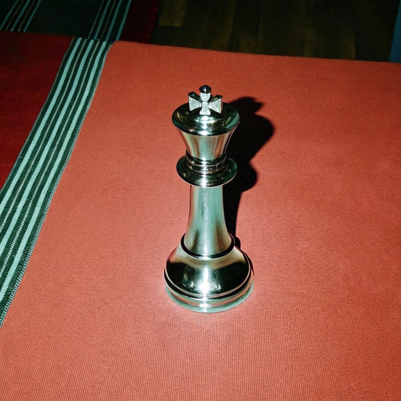 A silver king on a red baize board