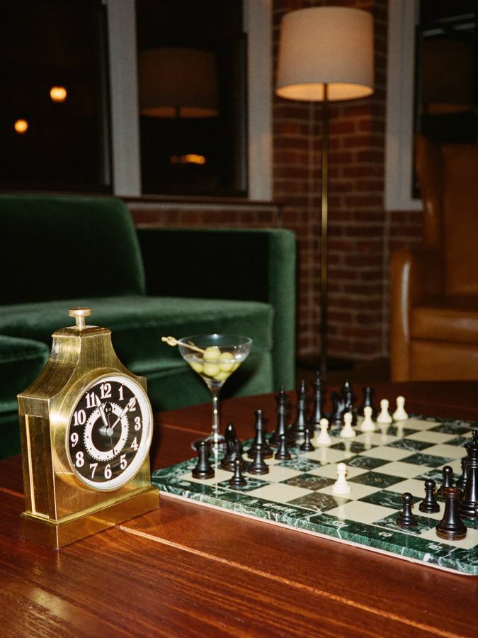 A brass chess clock beside a cocktail