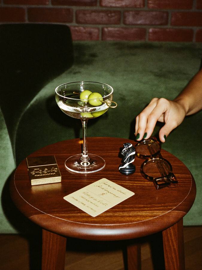 A martini, a chess piece and a card on a side table